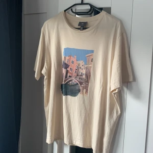 T-shirt med tryck - En beige t-shirt med en målad fin bild på. Lite oversized. Använd men i bra skick. 