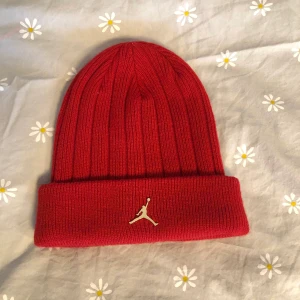 Jordan beanie  - Säljer denna då den inte längre kommer till användning. Använd kanske en termin, sparsamt använd. Neon röd, guld symbol. Storleken är one size.