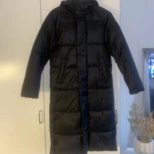 Lång vinterkappa - Säljer en sparsamt använd vinterkappa med tjock vaddering från SVEA i mycket fint skick. Jackan har en tvåvägsdragkedja och tryckknappar nedtill på sidorna. Jackan är helt felfri!