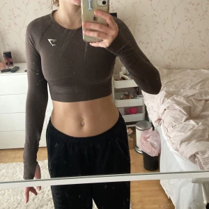 Gymshark - Vital seamless 2.0 long sleeve crop top  - Brun fin cropad träningströja från Gymshark. Storlek S, säljer den för att den är lite för liten för mig. Inte jätte använd och därmed i bra skick. Ordninarie pris 449 men säljer för 90 kr. Köparen betalar eventuell frakt. 