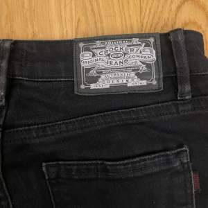 Svarta utsvängda jeans från märket Crocker. Jeansen sitter lite lågmidjat, är tajtare vid låren och svänger sedan ut efter knäna. Längst ner är de lite slitna men ser ändå bra ut. (Säljs pga för små).