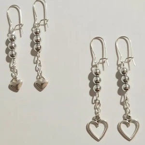 Öronhängen  - Fina silverfärgade örhängen.  Hemmagjorda av mig. Satt ihop pärlor och väldigt små silvriga ringar med ett hjärta i eller nycklar. Finns endast 1 par med nycklarna.  Köparen betalar frakten.  Säljes per par. Alla delar är köpta som nickelfria. 