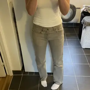 Beige/grå vintage jeans, uppsprättade nere för att vara längre därav fransiga. 