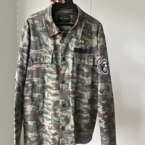River Island militärjacka  - Tunn kamouflagejacka från River Island. Står L i storlek men passar M också.