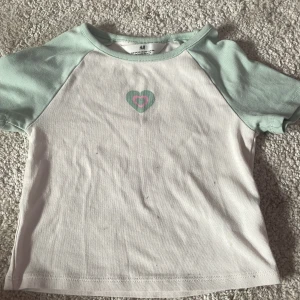 Grön hjärta croptop - En croptop från h&m, den har ett grön litet hjärta.  Har små små fläckar men syns inte när man har på Tvättas och stryks innan skick 