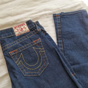 True Religion Jeans  - Superfina True Religion jeans i en snygg mörk tvätt. Fina fickor där bak och bra skick. Strl 27. Rak/utsvängd modell. Midja rakt över 38 cm Innerben 87 cm. Ytterben 105 cm