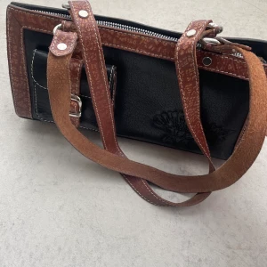 Väska, skinn - Snygg läderväska, i brunt och svart: Banden passar över axeln eller i handen och väskan liten-medelstor och passar till många tillfällen. Kan skicka mått och fler bilder på förfrågan. 