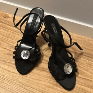 Klackar/pumps från Asos - Snygga klackar från asos i svart material med en sten i mitten. Riktigt eleganta! Använda endast ett fåtal gånger.