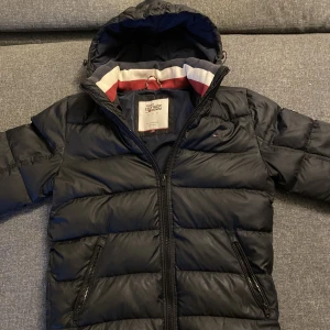 Tommy hilfiger jacka - Säljer för hittar ny och mest renar hallen nu, säljer billigt för ett litet hål i ryggen som jag lagat men syns knappt som du kan se på sista bilden, jackan är väldigt mörk blå