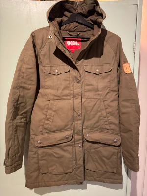 Fjällräven Parkas - Klassisk fjällrävenjacka, tunt fodrad. Ett minimalt hål pä ena framfickan