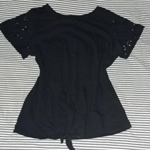 Snygg svart topp från H&M - Snygg kortärmad topp med knytning från hm i bra skick, använd få gånger säljer pgr av att jag inte använder den längre🩷