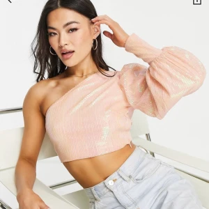 Oneshoulder topp - Rosa paljett tröja med one-shoulder från asos. Liten i storleken. Helt oanvänd, har prislappen kvar. Orginalpris: 689kr 