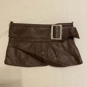 Brun väska  - Handväska/Kuvertväska i brun färg. Lite sliten vid kanten (bild visar). I övrigt: fin väska!