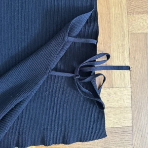 Svart topp - Svart topp med hög hals , och öppen på sidorna med knytning! Jätte fint skick, använd fåtal gånger. (Frakt tillkommer) 