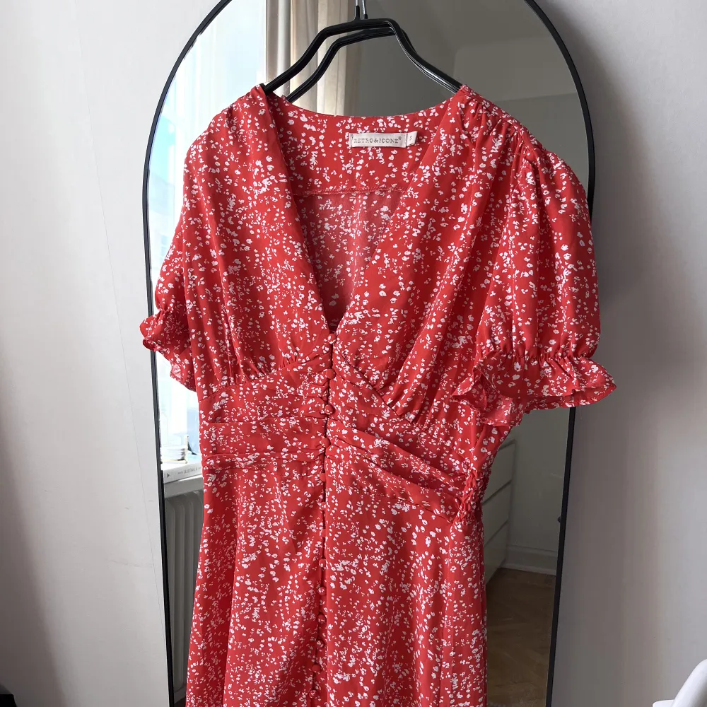Röd/vit blommig klänning från märket Chelsea. Små knappar framtill. 100% polyester. 85 cm längd. Nypris 699kr. Använd enstaka gånger.. Klänningar.