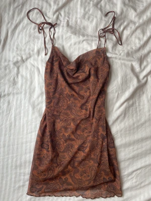 Brun klänning - Brun mönstrad klänning från Bershka i marbella, en favorit som jag fått många komplimanger i men tyvärr lite liten för mig nu:( Man knyta söta rosetter vid bandet.