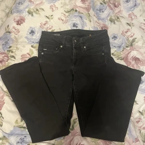 Lågmidjade svarta jeans - Säljer dessa svarta lågmidjade jeans ifrån g-Star raw då det har blivit för korta för mig som är 166 cm. Det har inga defekter och har en extra knapp vid gylfen (se bild 3). Innerbenslängden är 73 cm och midjemåttet tvärs över är 34 cm 💓💓