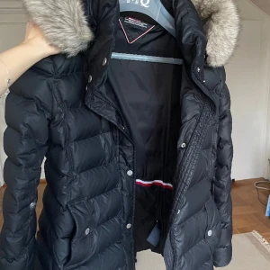 Tommy Hilfiger dunjacka - Mörkblå i storlek L, (M/L) använd en vinter så fortfarande i fint skick.  Enda är att det är en dunjacka så såklart händer det att en och annan dunfjäder släpper med tiden. Pälsen på luvan går att ta av och har hållit sig som ny. 