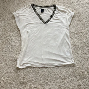 Vit blus med svart tryck - Säljer denna jättegulliga blusen/t-shirten då den är för stor. Den har andvändts ett flertal gånger men är i ett hyfsat bra sick.