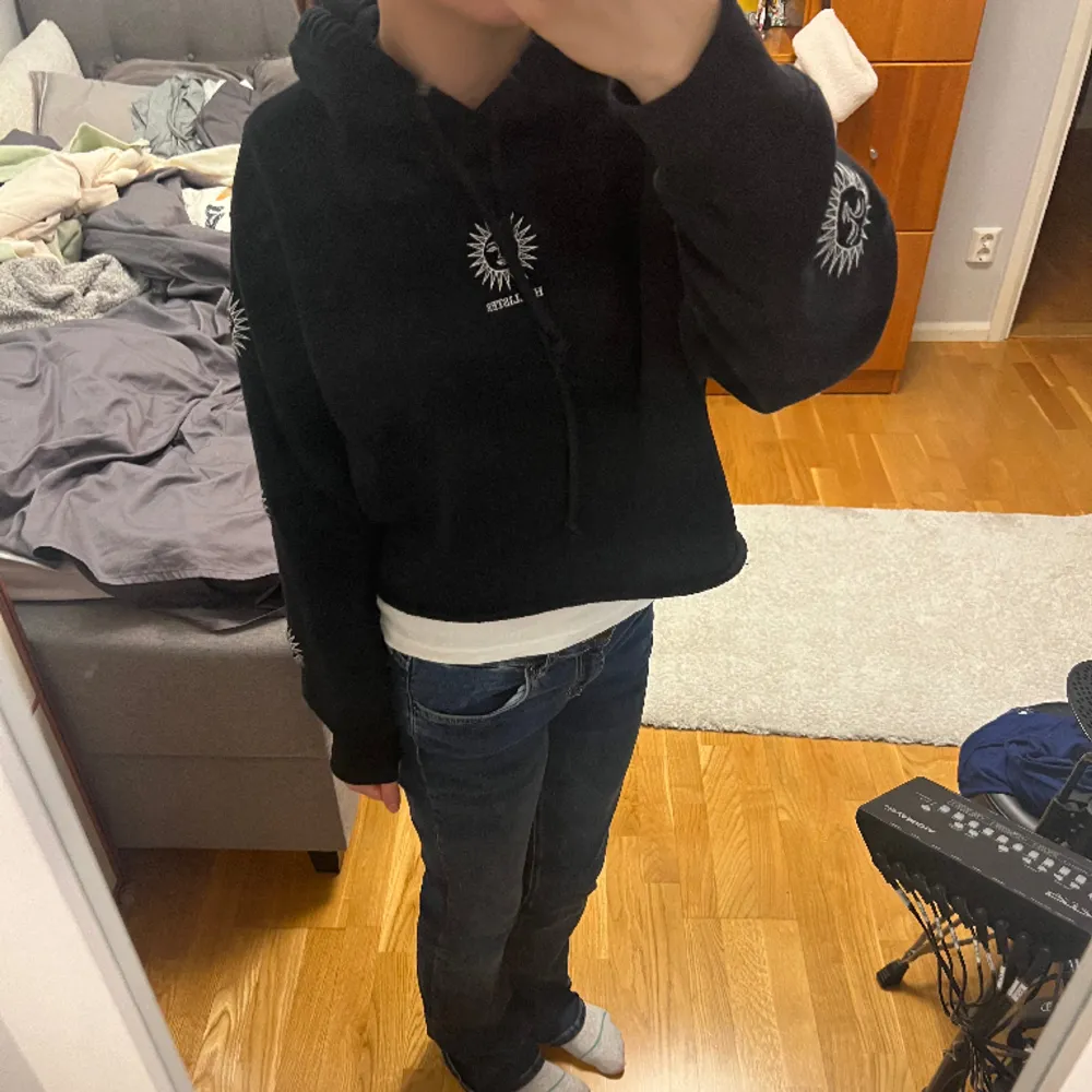 Snygg cropped svart luvtröja från Hollister i strl M med små solar på ärmarna. Passar mig som är strl S. Ny skick och säljs inte längre💘. Hoodies.