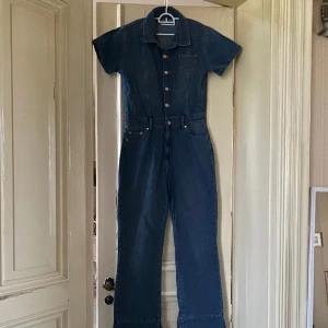 Jumpsuit - Mörkblå jumpsuit med fickor. Passar som en stlk 38-40. 