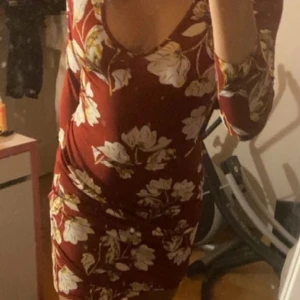 Klänning - Väldigt skön röd klänning med blommor använd två gånger + på bilden storlek s? Men väldigt strechiga har samt ett band som man kan knyta lite hur man vill