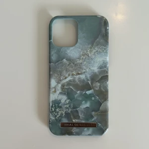 Mobilskal - Fint skal från idealofsweden till Iphone 12/ 12 pro! Fint skick förutom en liten fläck på insidan. Köparen betalar för frakten och katt finns i hem 🏡 