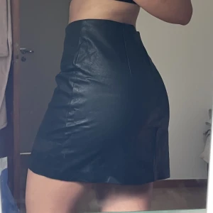 Svart läderkjol  - Svart läderkjol med slits i fram som tyvärr är för stor för mig. Aldrig använd!