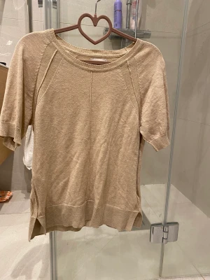 Stickad T-shirt - Säljer en guld/beige tunt stickad T-shirt i mycket fint skick.  Använd ett par gånger , inga fläckar eller hål.  Pris kan diskuteras!
