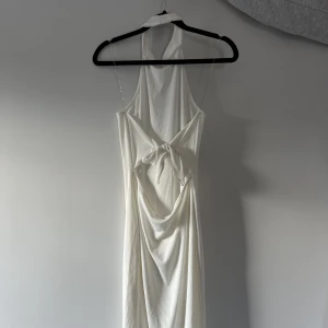 FashionNova Långklänning - En vit knä-långklänning ifrån FashionNova strl M, sitter figurtight med öppen rygg och knytdetaljer, jättefin att ha en utkväll eller middag!🤍 Säljs för att den inte använts