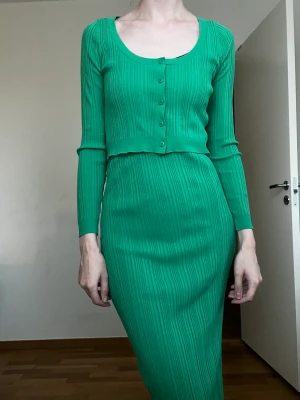 Ribbad kofta / topp - OBS! Har gått sönder i ärmen, jag har lagat det efter bästa förmåga med symaskin men det syns att det är en lagning. Därav priset. Finstickat tyg. Ribbad design. Figursydd design. Cropped design. Rund krage. Lång ärm. Knäppning på framsidan. Total look.  