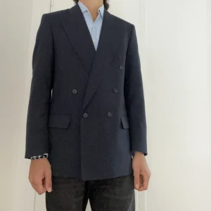 Dubbelknäppt kavaj - Säljer denna randiga dubbelknäppta kavajen från regency då den ej kommer till användning längre. Storlek 46 sitter lite större, bra skick. Färgen är mörkblå med kritstreck ränder u tonerna blå och röd. 