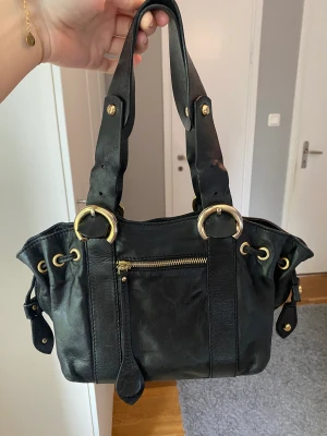 Svart axelväska  - Svart axelväska som jag säljer då den inte kommer till användning. Längd: 25-32 cm (justerbar),  höjd: 18cm, vidd: 10cm.