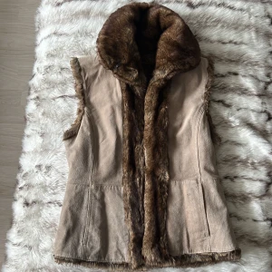 Vändbar väst från MQ - Vändbar väst i fuskpäls och läder från Zoul MQ. Storlek S. Observera att det är en pytteliten fläck på ena sidan vid fickan, därav det låga priset. 