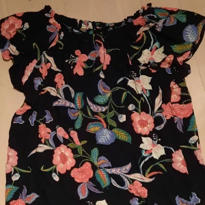 Blommig blus - Svart blus med härligt blommigt mönster. Säljes då den inte kommer till användning. Hör gärna av dig vid frågor eller funderingar. 