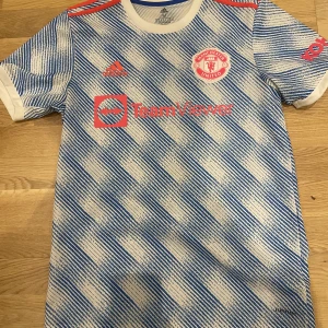 Manchester United tröja 21/22 - En man United tröja med elanga på ryggen, använd 3 gånger typ, köpt från man United hemsida, säsong 21/22 bortaställ, nyskick.  Köpt för typ 800 för 2 år sedan