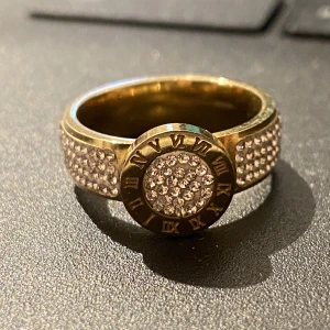  Guldring i rostfritt stål - Guldring i rostfritt stål med diamanter och en detalj med romerska siffror i mitten!