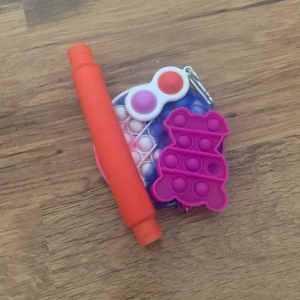 Ett kit med fidget toys - 1 vanlig popit använd få gånger, 1 mini popit använd 1 gång, 1 tupe toy och en grej du kan trycka in och ut.