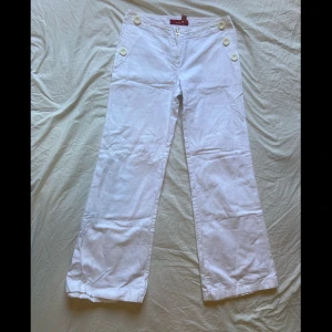 Vita jeans  - Vita somriga jeans med knappar på höfterna, en knapp saknas. Fina fickor, midrise. 