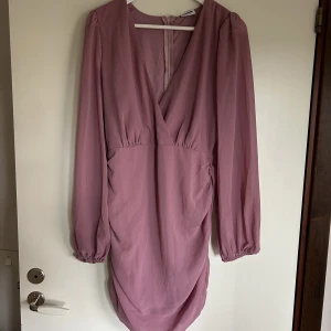 Festklänning  - En kort romantisk festklänning, dragkedja i ryggen så den är lätt att få på. Långa genomskinliga ärmar. Dubbeltyg på resten av kroppen, så ej genomskinlig. Storlek L men är liten i storleken. Skulle säga M. 