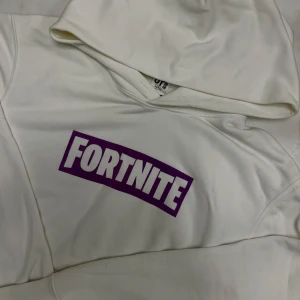 Fortnite Hoodie Vit/Lila - Vit hoodie m Fortnite-logga från Uniqlo. Gott skick. Storlek S men passar även större
