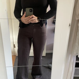 Brunrandiga lågmidjade kostymbyxor - Snygga knappt använda lågmidjade randiga kostymbyxor i brunt! Står ingen storlek men skulle säga att de passar en storlek 36. Hör av dig om du är intresserad eller har några frågor!🤗