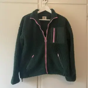 Mörkgrön fleece/kofta med ljusrosa dragkedjor från America Today. Snygg öppen och halvt eller helt uppdragen då den går upp i kragen.  Köpt i Amsterdam för ca 400kr 🙌 Köparen står för frakten eller möter upp i Stockholm 