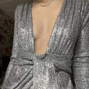 En superfin paljettklänning i färgen grå som inte är använd, bara provad. Relativt kort utan att visa häcken för oss längre. Klänning i bra skick. Kanske årets nyårsklänning? 