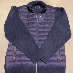 Mörkblå cardigan  - Säljer en mörkblå cardigan från leon marcel stickade ärmar och quiltad front. Jackan har dragkedja framtill och två fickor med dragkedja. Perfekt för kyliga dagar och snygg till jeans. Den här jackan är helt ny och aldrig använd jag säljer den för jag beställde fel storlek och man svarar inte på min mejl så jag kan inte lämna tillbaka. Den är med prislapp den är i storlek M 