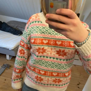Mönstrad stickad tröja från Lindex - Supermysig stickad tröja från Lindex med juligt mönster i rött, grönt och vitt. Tröjan har rund halsringning och långa ärmar, perfekt för kalla dagar och vintersäsongen.org pris:300kr