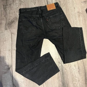 Svarta Levis 501 jeans - Klassiska svarta Levis 501 jeans med raka ben och femficksdesign. Jeansen har knappgylf och Levis Premium-märke på insidan.