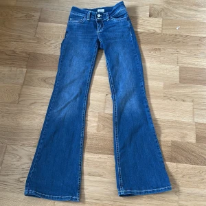Blå bootcut jeans från Nelly - Blåa bootcut jeans med två knappar och brodering på fickorna mycket fint skick inga hål eller slitningar, använda fåtal gånger. Från Nelly Low Waist Bootcut Stitch Jeans Nypris 699kr