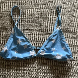 Blå bikini med stjärnmönster - Snygg blå trekantsbikini med vita stjärnor. Justerbara axelband. Aldrig använd