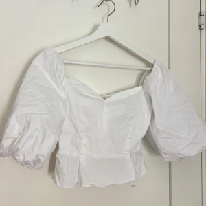 Vit blus med puffärmar - Säljer en vit blus med stora puffärmar och markerad midja. Toppen har en söt, feminin form och är perfekt för dig som gillar trendiga detaljer. Passar till många olika stilar och är lätt att matcha med både jeans och kjol.